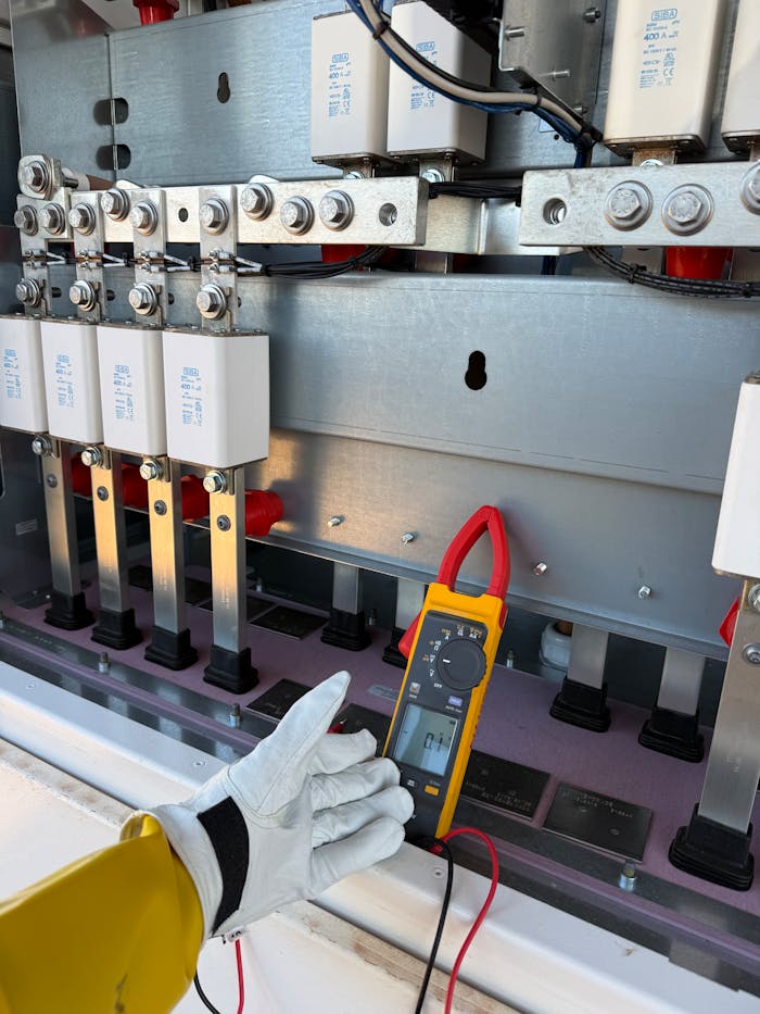 Technician using multimeter to measure voltage in an electrical panel. Professional outdoor maintenance.
