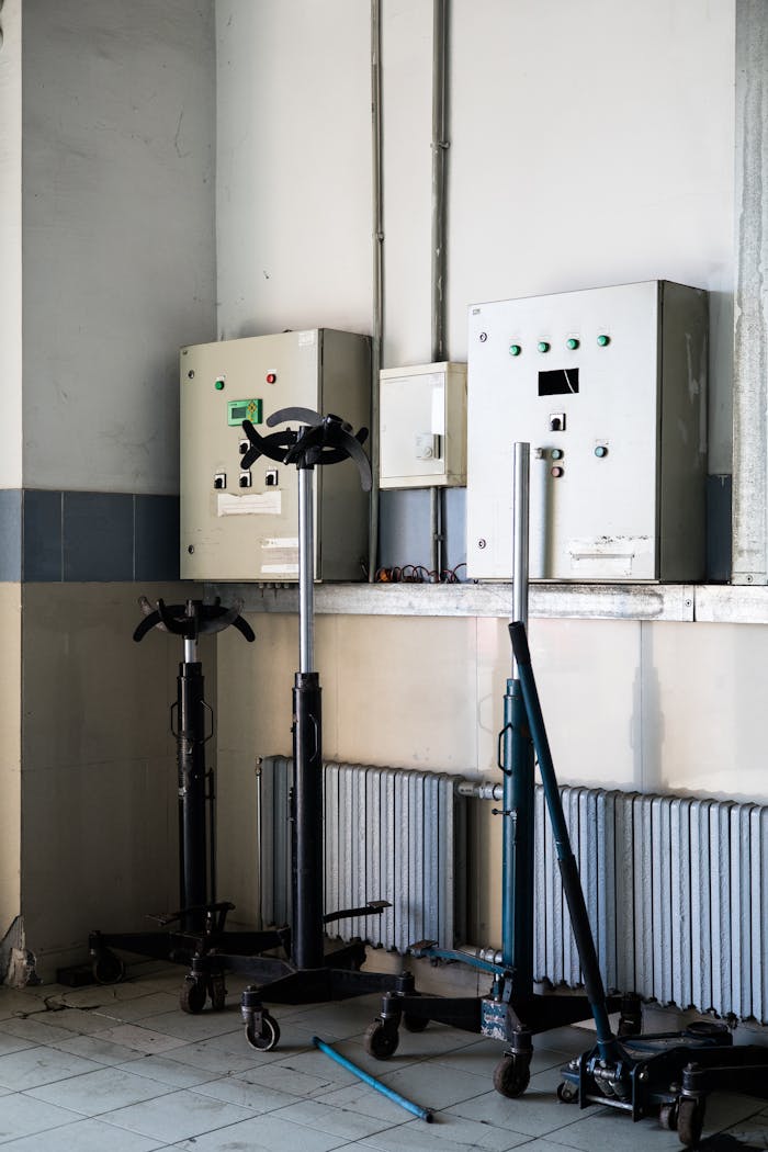 An industrial workshop with tools and electrical panels lined against a wall.